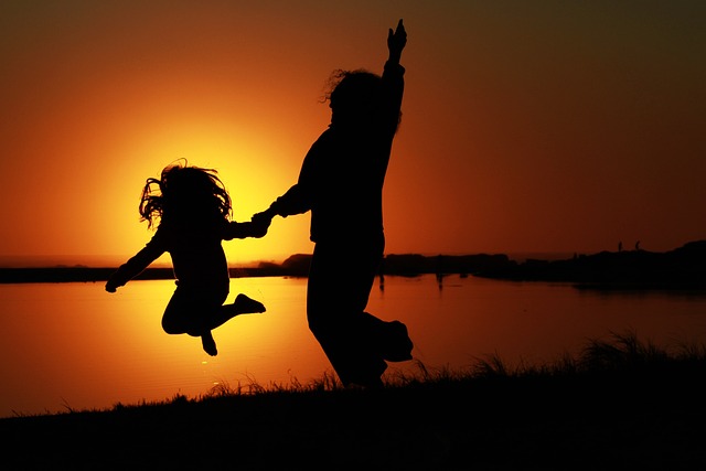 Un enfant et une personne plus agée qui sautent de bonheur. Ils sont plein de vitalité.